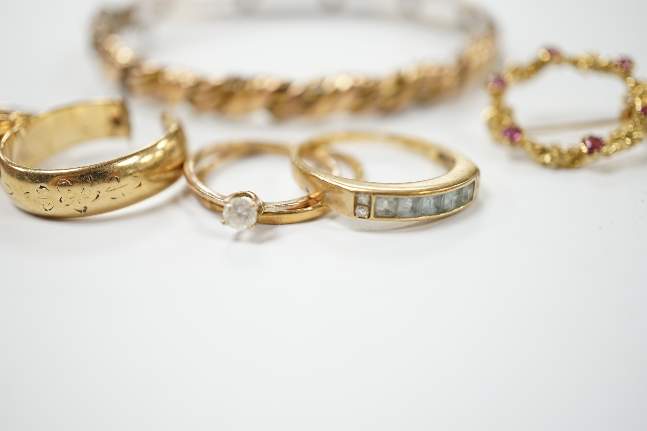 An early 20th century 9ct hinged bangle, three assorted 9ct gold rings and a modern 9ct gold and gem set brooch and two other yellow metal rings, gross weight 23.2 grams. Condition - poor